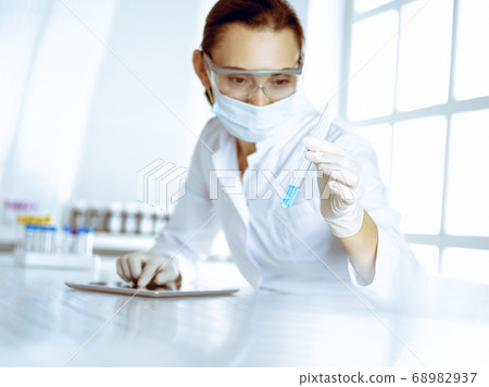 Female laboratory assistant analyzing test tube with blue liquid. Medicine, health care and researching concept 68982937