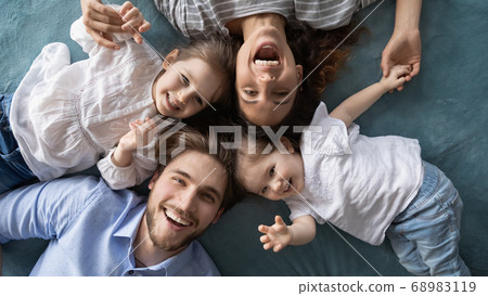 Happy young parents relaxing on bed with joyful little daughters. Happy young parents relaxing on bed with joyful little daughters. 68983119