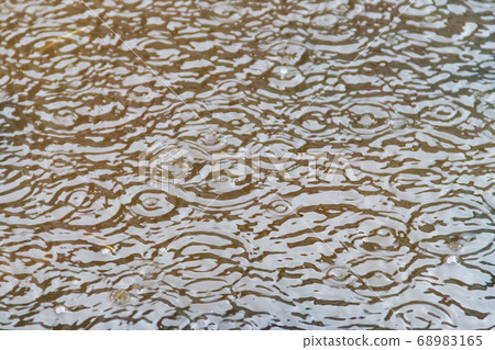 Puddle of water with splashing raindrops 68983165