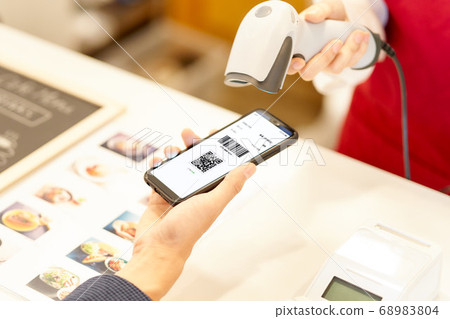 Hand of a clerk who reads the barcode displayed on the smartphone 68983804