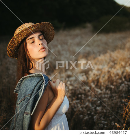 Young cute freckled woman walking in summer meadow Young cute freckled woman walking in summer meadow 68984457