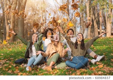 Young multiracial friends playing with autumn leaves in park Young multiracial friends playing with autumn leaves in park 68984837