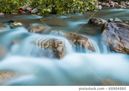 Little cascade falls of water over mountain river 68984860
