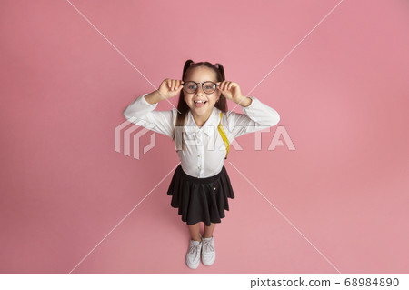 Success in school. Smiling little schoolgirl with glasses and backpack shows tongue and have fun 68984890