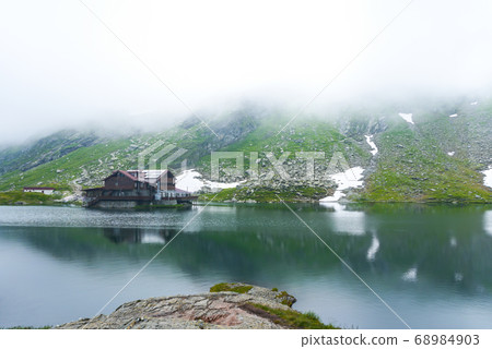 Majestic hose in fog, lake in mountains of Balea 68984903