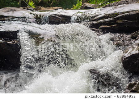 Clear river running fast, hitting rocks. Clear river running fast, hitting rocks. 68984952