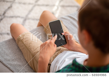 Teen guy holding mobile phone with empty screen, closeup Teen guy holding mobile phone with empty screen, closeup 68984966