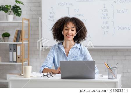 Teacher works online during quarantine. Woman chatting with students at online lesson in living room Teacher works online during quarantine. Woman chatting with students at online lesson in living room 68985244