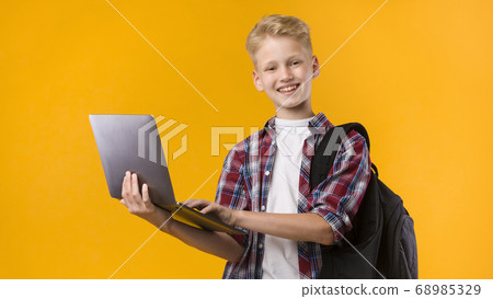Happy guy holding laptop at yellow studio 68985329