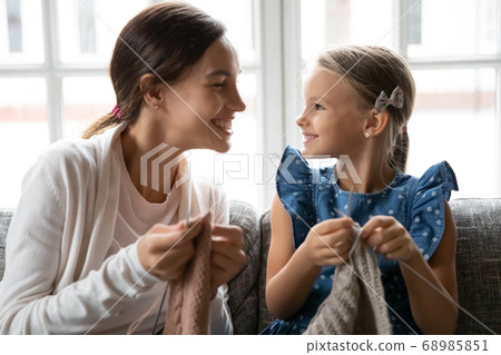 Young biracial woman teaching little child daughter knitting. Young biracial woman teaching little child daughter knitting. 68985851