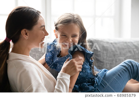 Overjoyed young woman having fun with laughing little daughter. Overjoyed young woman having fun with laughing little daughter. 68985879