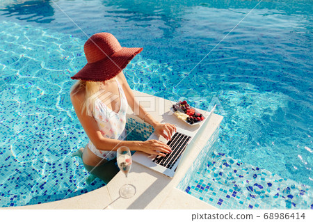 woman using laptop and relax at swimming pool 68986414