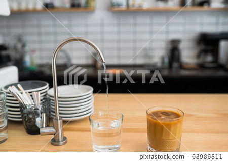 water is pouring from a tap into a glass 68986811