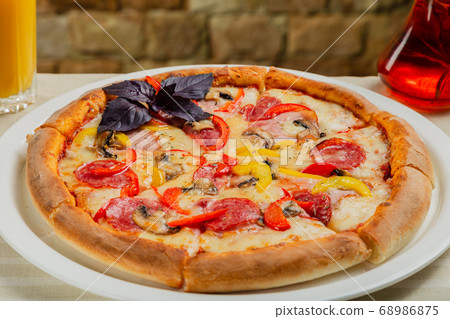 Fresh hot pizza on white plate in restaurant. Fresh hot pizza on white plate in restaurant. 68986875
