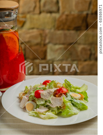 Fresh caesar salad in a white plate on the table. 68986971
