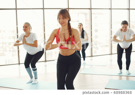 Pregnant women doing yoga with a coach Pregnant women doing yoga with a coach 68988368