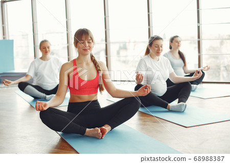 Pregnant women doing yoga with a coach 68988387