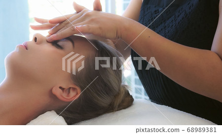 Woman gets facial and head massage in luxury spa. 68989381
