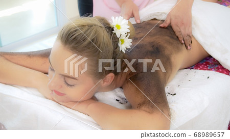 Relaxed woman lying on spa bed for body scrubbing. Relaxed woman lying on spa bed for body scrubbing. 68989657