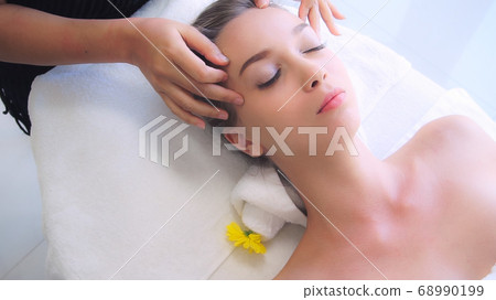 Woman gets facial and head massage in luxury spa. Woman gets facial and head massage in luxury spa. 68990199