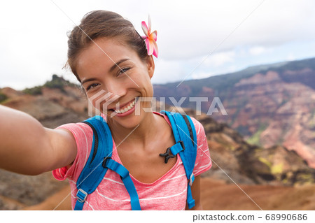Selfie travel tourist hiker girl in Waimea Canyon Hawaii hike taking self-portrait picture with camera phone having fun hiking in Kauai mountains, Hawaii. Woman taking photos on adventure travel Selfie travel tourist hiker girl in Waimea Canyon Hawaii hike taking self-portrait picture with camera phone having fun hiking in Kauai mountains, Hawaii. Woman taking photos on adventure travel 68990686