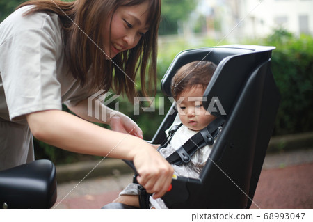 Mother carrying a child on a bicycle Mother carrying a child on a bicycle 68993047