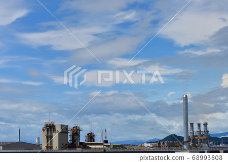 Four chimneys emitting white smoke in the blue sky 68993808