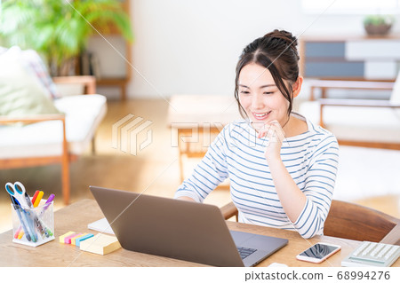 Young woman doing telework in the living room Young woman doing telework in the living room 68994276