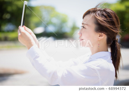 A woman shooting with a smartphone A woman shooting with a smartphone 68994372