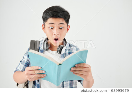 Shocked schoolboy reading book 68995679