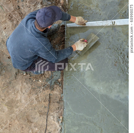 Workers pour concrete solution at a construction 68998075