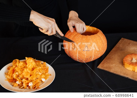Jack's Halloween pumpkin. Girl's hand with a knife cutting an orange pumpkin Jack's Halloween pumpkin. Girl's hand with a knife cutting an orange pumpkin 68998641