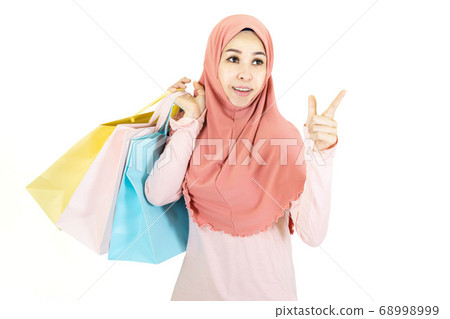 Happy beautiful young muslim asian woman with traditional dress holding color shopping bag isolated on white background Happy beautiful young muslim asian woman with traditional dress holding color shopping bag isolated on white background 68998999