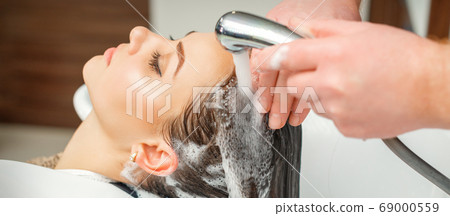 Hands of hairdresser washing hair of woman 69000559