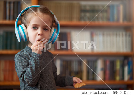 Cute Caucasian little girl in big white headphones 69001061