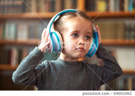 Cute Caucasian little girl in big white headphones Cute Caucasian little girl in big white headphones 69001062