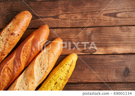 Three crispy french baguettes lie on an old wooden Three crispy french baguettes lie on an old wooden 69001134