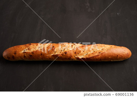 one crispy french baguettes lie on an old wooden 69001136
