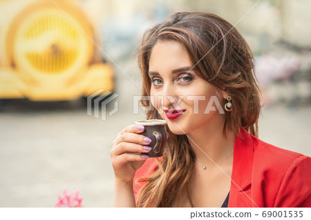 Beautiful girl having coffee at cafe outdoors. 69001535
