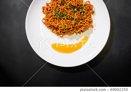 Korean spicy hot instant noodles on a black background, picture from the top view of instant noodles 69002250