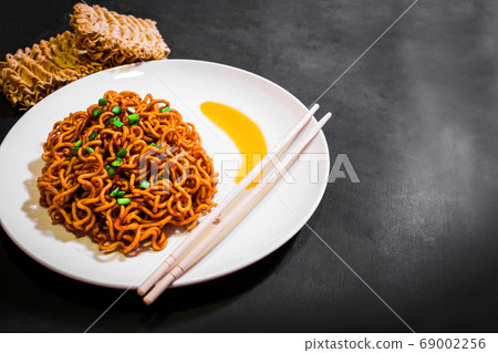Korean spicy hot instant noodles on a black background, picture from the top view of instant noodles Korean spicy hot instant noodles on a black background, picture from the top view of instant noodles 69002256