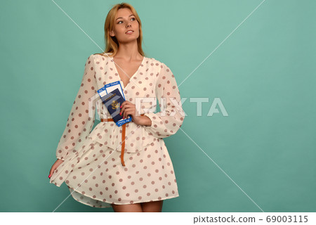 Joyful young woman in polka dot dress is holding 69003115