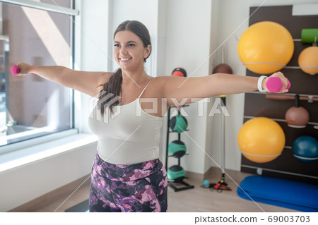 Woman doing exercises with dumbbells in gym 69003703