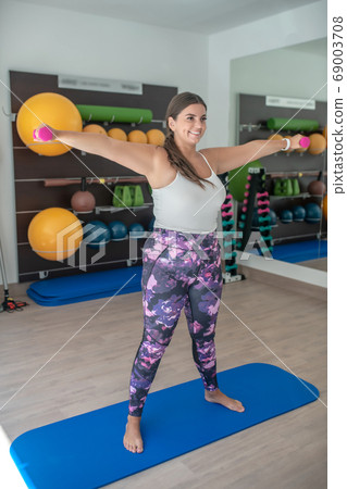Plus-sized woman practising yoga asanas in a gym Plus-sized woman practising yoga asanas in a gym 69003708