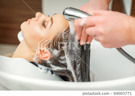 Hands of hairdresser washing hair of woman Hands of hairdresser washing hair of woman 69003771