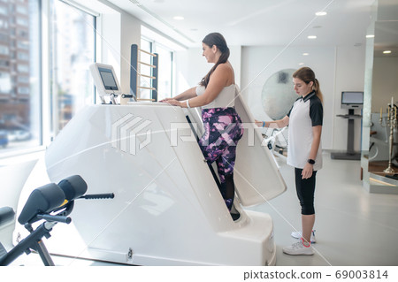 Plus-sized woman learning to use sports equipment with the instructor 69003814