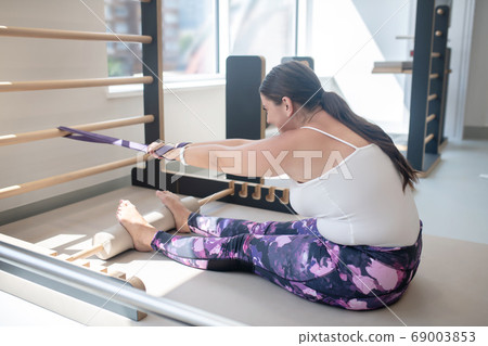 Woman trying to stretch her muscles with special equipment 69003853