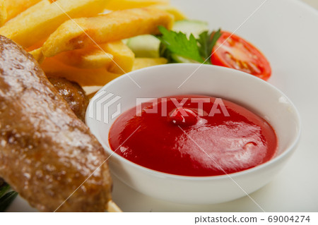 Freshly fried kebab with fried potatoes and tomato Freshly fried kebab with fried potatoes and tomato 69004274