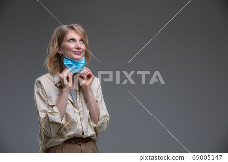 Blond woman take off her surgical mask Blond woman take off her surgical mask 69005147