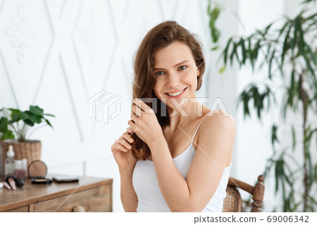 Happy young woman touching her silky hair Happy young woman touching her silky hair 69006342